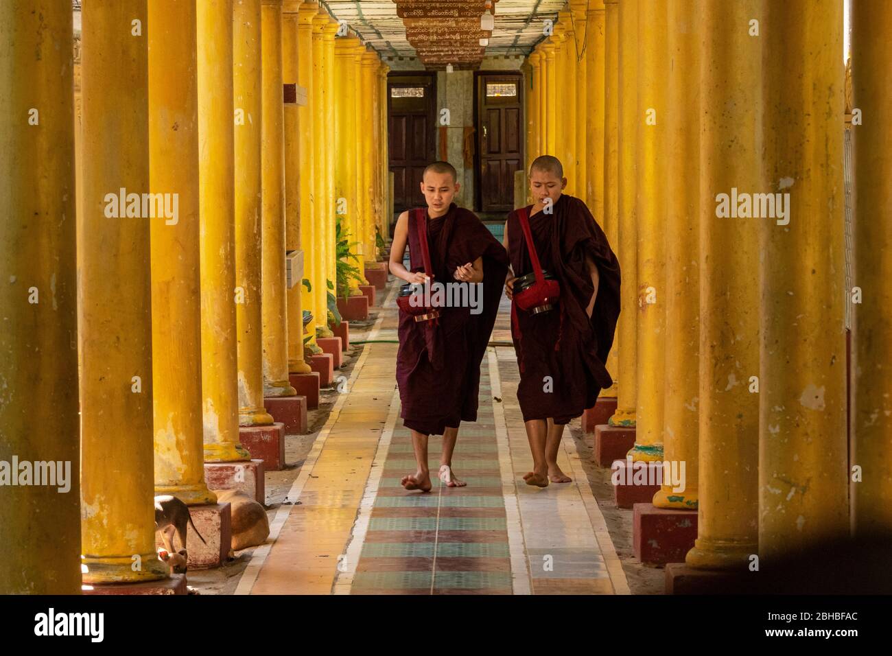 Deux Monks marchant parmi la ligne de colonnes au temple bouddhiste Banque D'Images