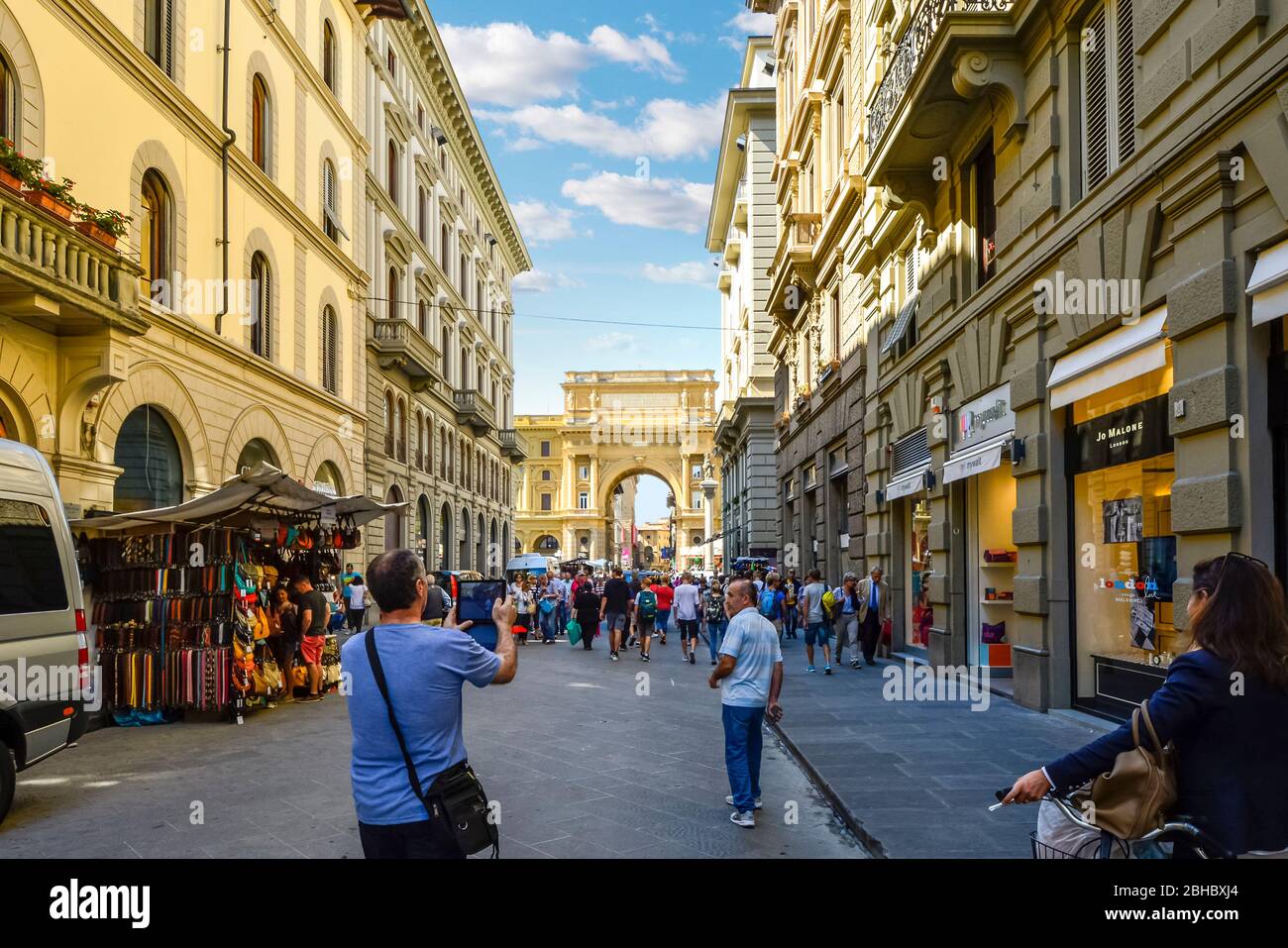 L'homme de prendre une photo avec une tablette comme il suit un groupe de personnes à marcher en direction de la Piazza della Repubblica à Florence Italie Banque D'Images