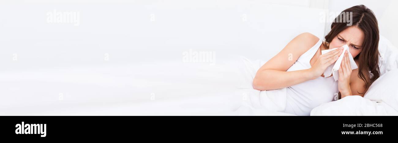 Femme ayant une allergie ou une grippe dans le lit éternuer à la maison Banque D'Images