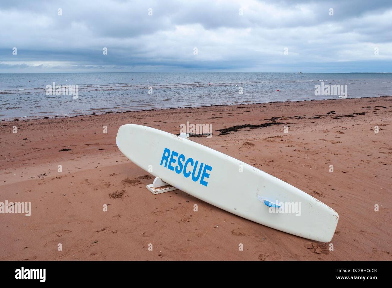 Planche de sauvetage sur une plage déserte en bord de mer. Eaux calmes sous un ciel couvert. North Rustico Beach, parc national de l'Île-du-Prince-Édouard, Canada Banque D'Images