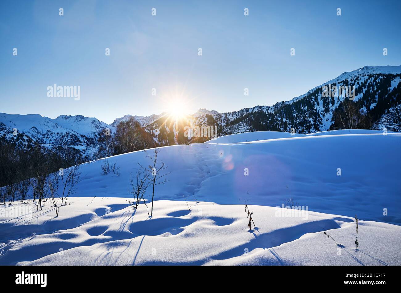 Lever du soleil dans les montagnes avec de la neige et des sommets élevés contre le ciel bleu Banque D'Images
