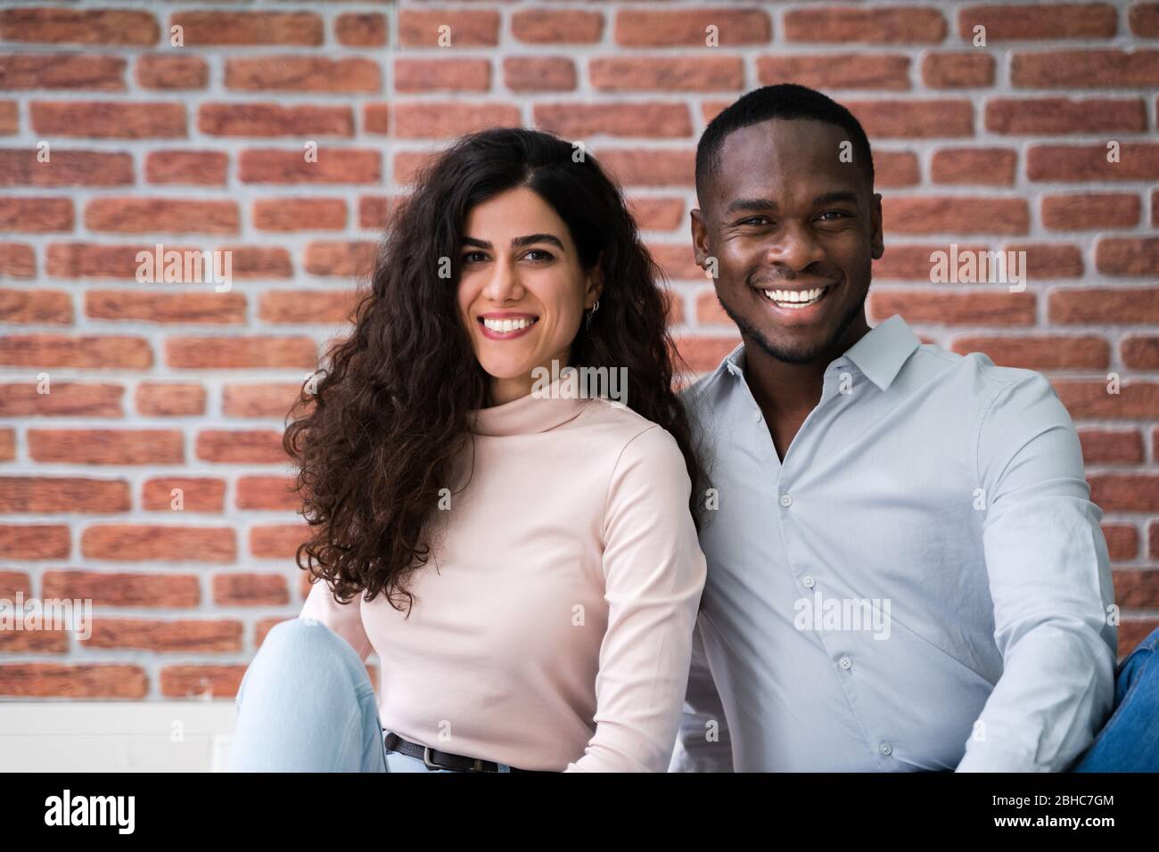Portrait de jeunes couples multiethniques assis sur le sol dans leur nouvelle maison Banque D'Images