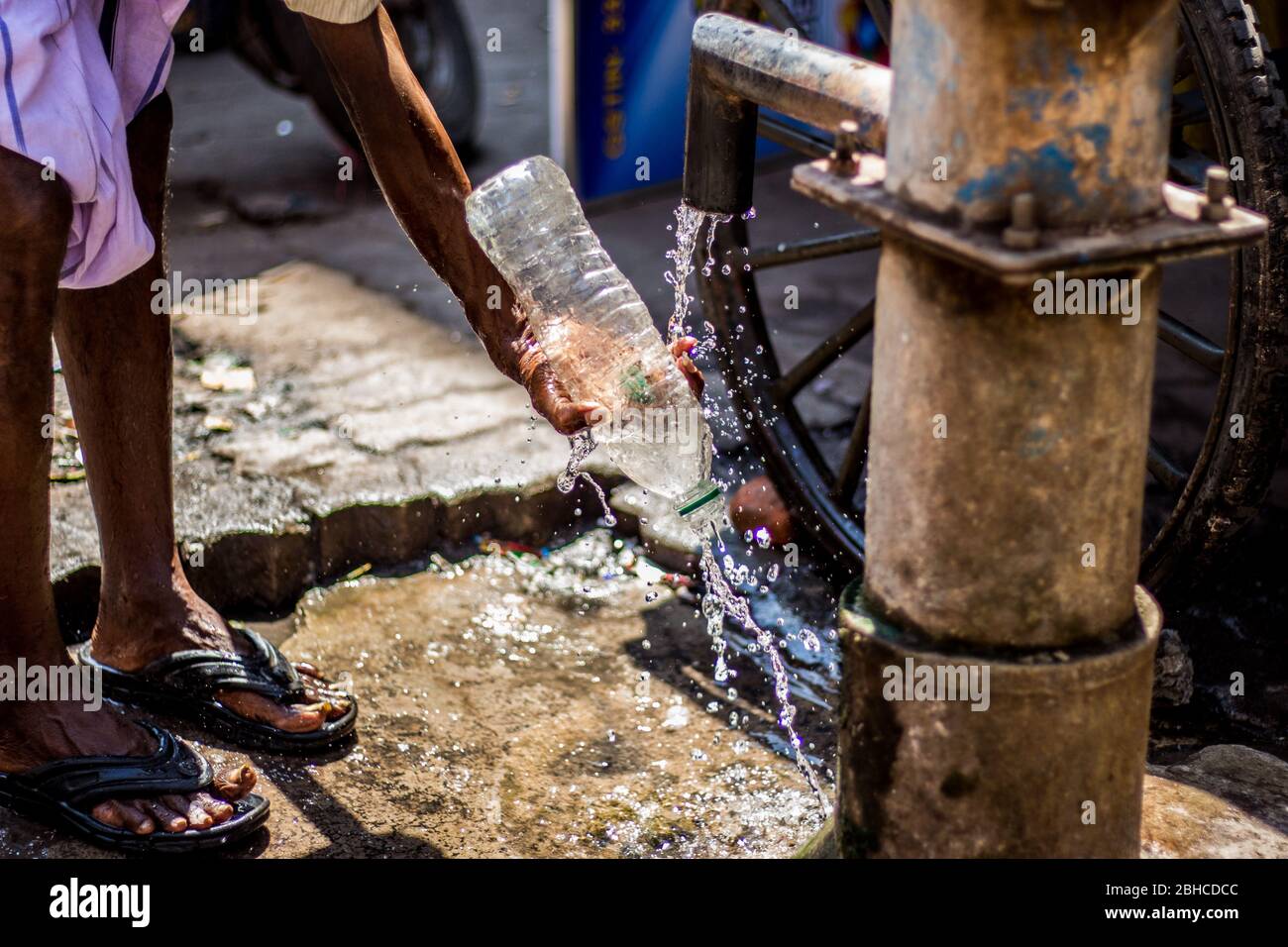 L'homme utilisant la bouteille d'eau ses mains à une pompe à eau manuelle dans la campagne indienne. Utilisation de la pompe à eau manuelle dans la rue. Pompe manuelle pour tirer sous le wat de masse Banque D'Images