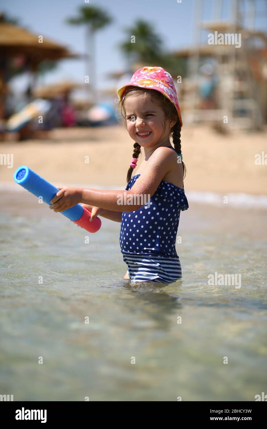Jolie fille caucasienne de quatre ans en maillot de bain jouant avec une pompe  à jouets dans la mer Photo Stock - Alamy