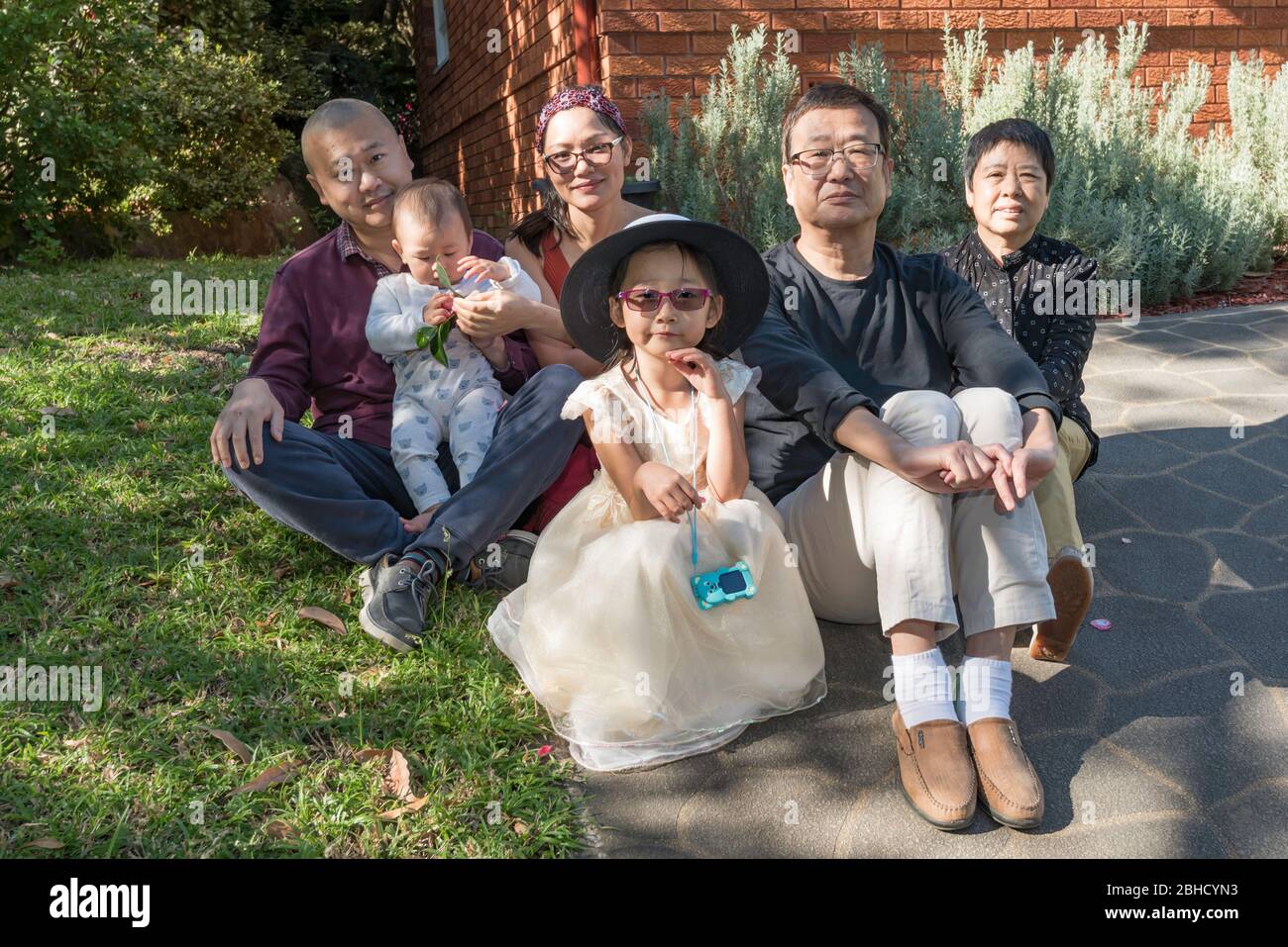 Une famille chinoise heureuse et étendue vivant en Australie s'assoit sur le chemin de leur maison de Sydney pendant l'épidémie de Covid-19. Banque D'Images
