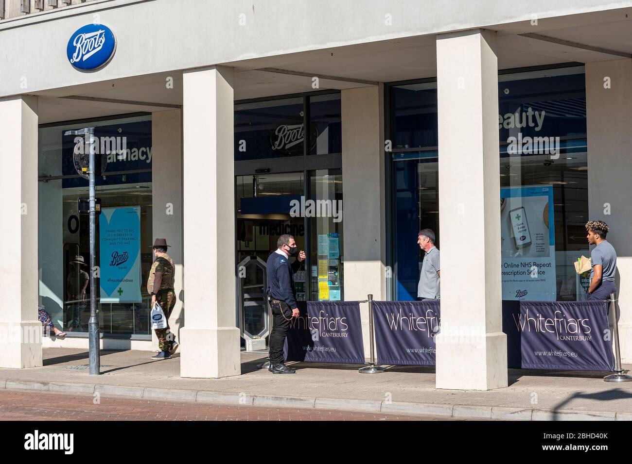 Les gens font la queue en dehors de la pharmacie Boots pendant le verrouillage de Coronavirus 19 à Canterbury, Kent UK, UN homme de sécurité porte un masque de visage. Banque D'Images Les gens font la queue en dehors de la pharmacie Boots pendant le verrouillage de Coronavirus 19 à Canterbury, Kent UK, UN homme de sécurité porte un masque de visage. Banque D'Images