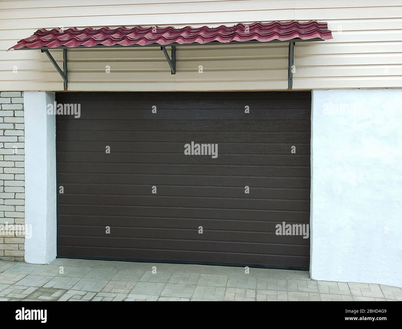 Les portes automatiques sombres dans le garage pour la voiture. Porte dans les locaux de brique et de béton Banque D'Images