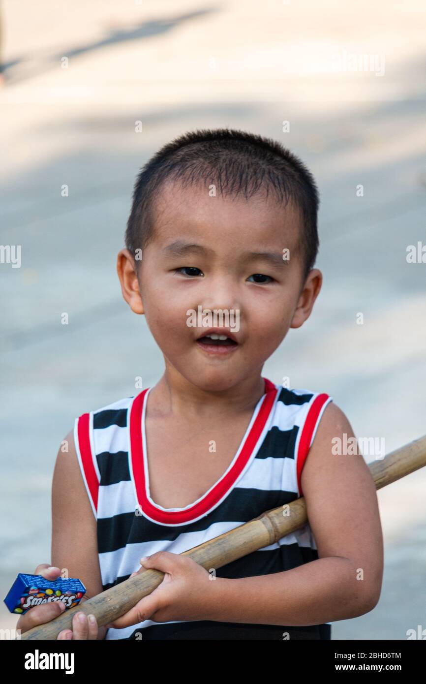 Jeune sourire âge scolaire enfant vietnamien portant la canne en bambou, sa Dec, Cai be, Vietnam. Asie Banque D'Images