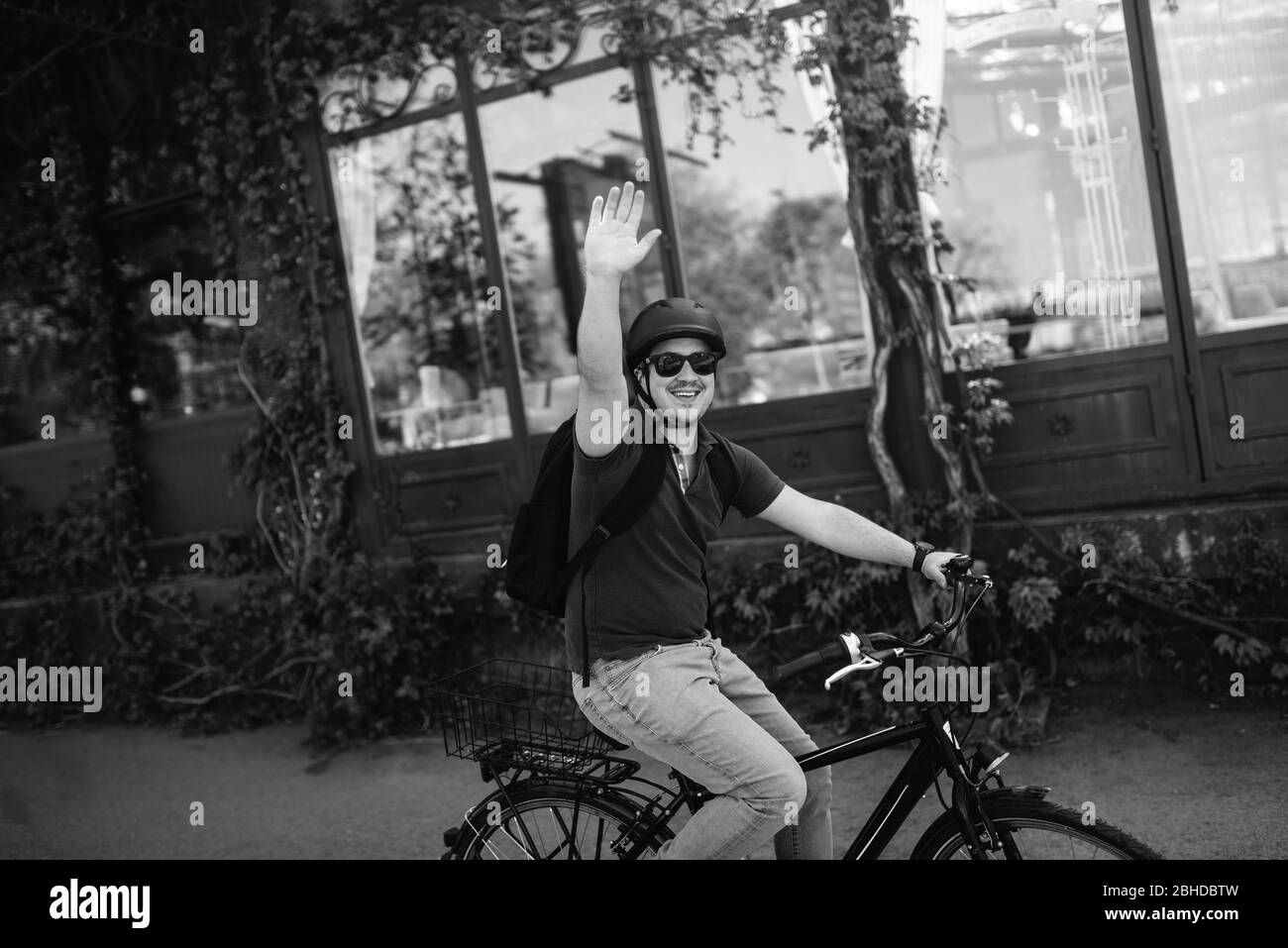 Jeune cycliste caucasien avec casque et lunettes de soleil sur un vélo devant les vagues de la fenêtre Banque D'Images
