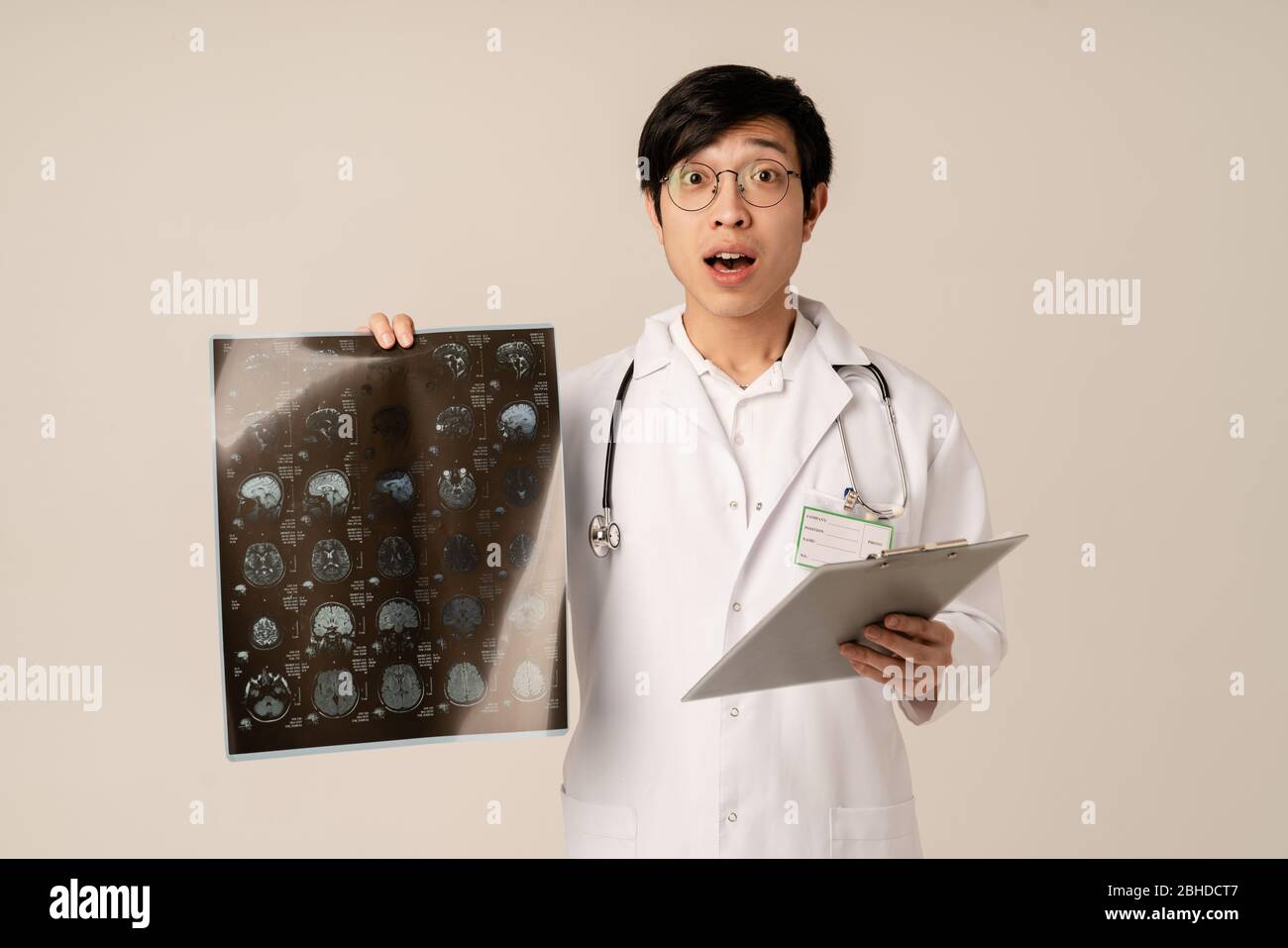 Image du jeune médecin asiatique en imagerie TDM à balayage radiographique uniforme, isolée sur fond beige Banque D'Images
