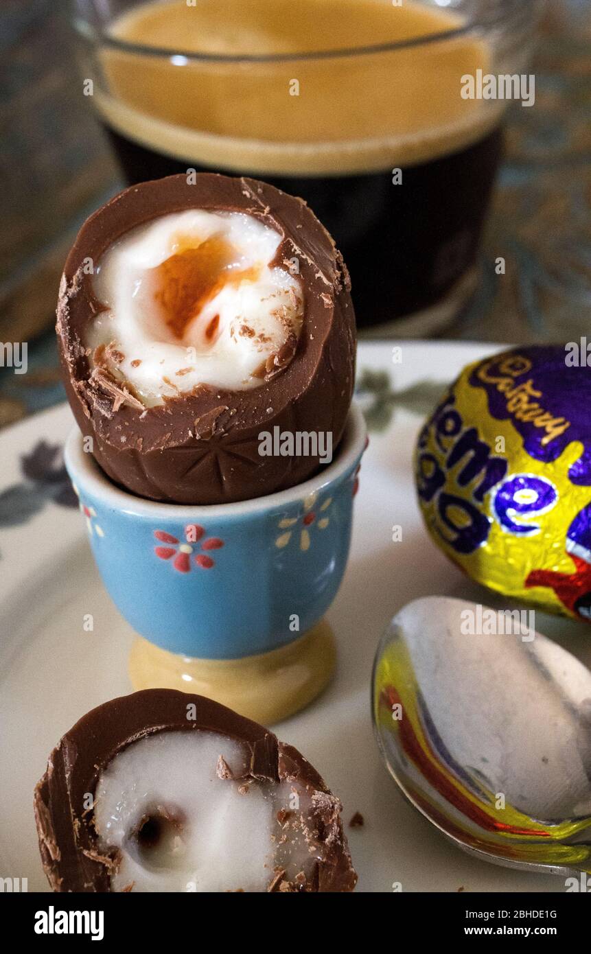 Joyeuses Pâques. Gros plan d'un œuf de Creme de Cadbury, ressemblant à un œuf bouilli dans une tasse d'œuf, accompagné d'un café expresso pour le petit déjeuner Banque D'Images