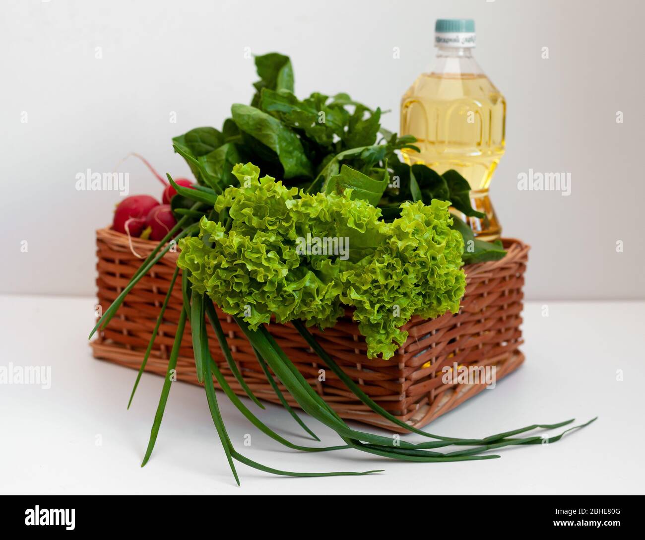 Livraison de produits. Boîte avec légumes et huile de tournesol. Un ensemble de légumes verts pour salade. Ciboulette, laitue, concombres, radis, épinards, arugula Banque D'Images