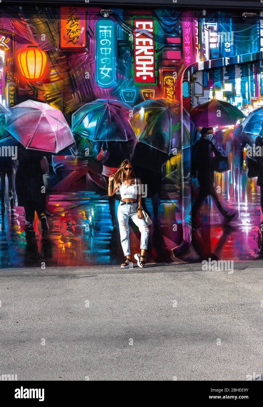 Portrait d'une jeune femme posant à côté d'un graffiti décoratif coloré, Wynwood Walls, Miami, Floride, États-Unis. Banque D'Images