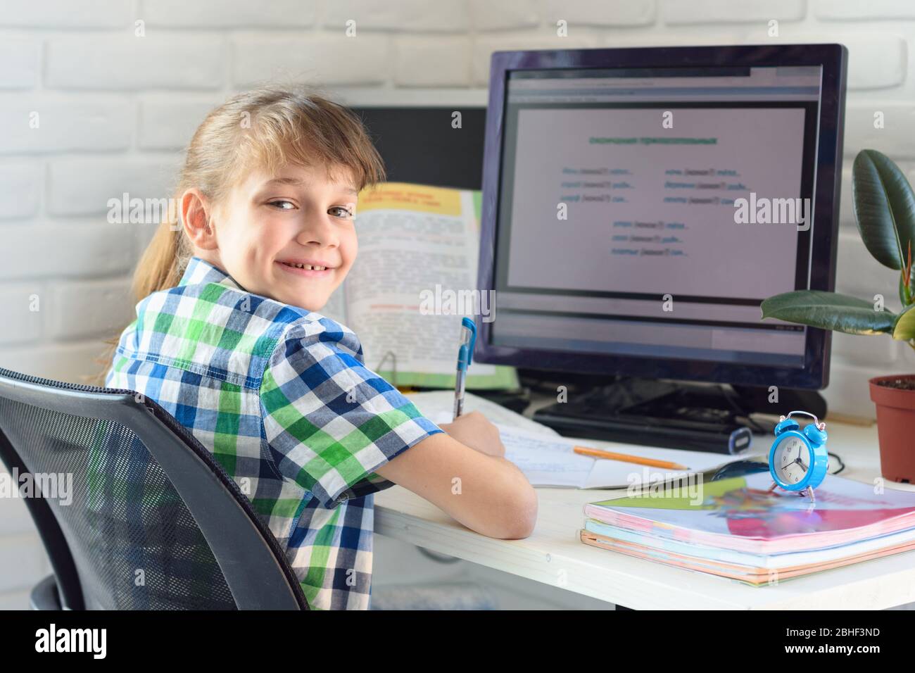 Un enfant satisfait est assis sur une table d'ordinateur et regarde dans le cadre Banque D'Images