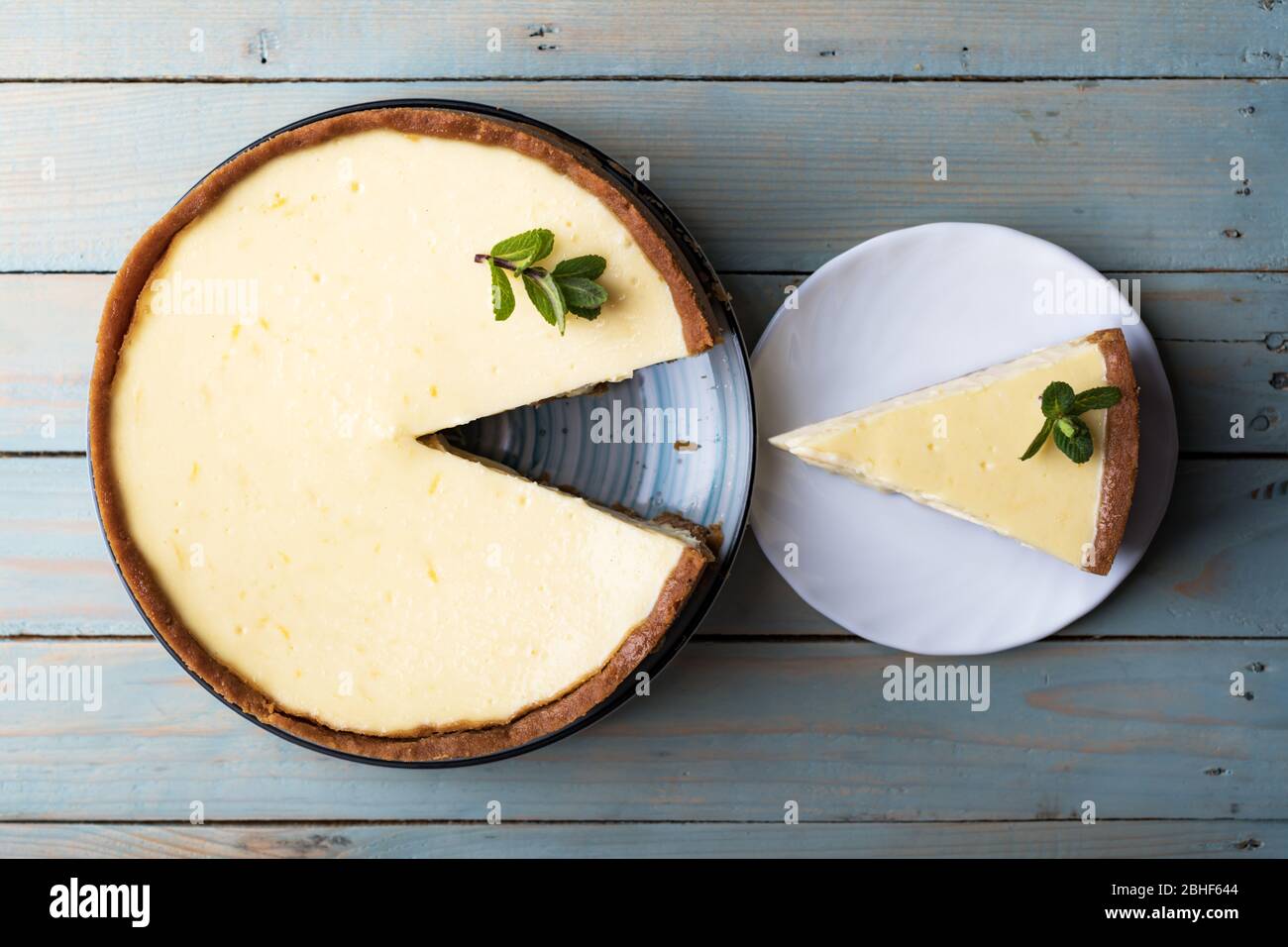 Un classique de New York à motif avion et sa tranche avec une branche de menthe sur une plaque sur une table en bois. Le concept de la boulangerie et des desserts aux gâteaux sucrés Banque D'Images