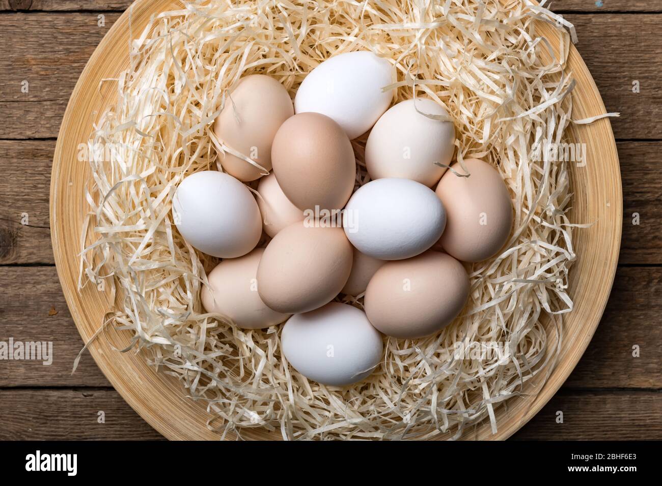 Œufs de poulet biologiques dans le nid sur fond de bois. Photographie alimentaire Banque D'Images
