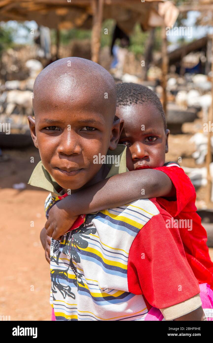 Garçon portant un petit frère sur un marché animal près de Banjul, Gambie. Banque D'Images