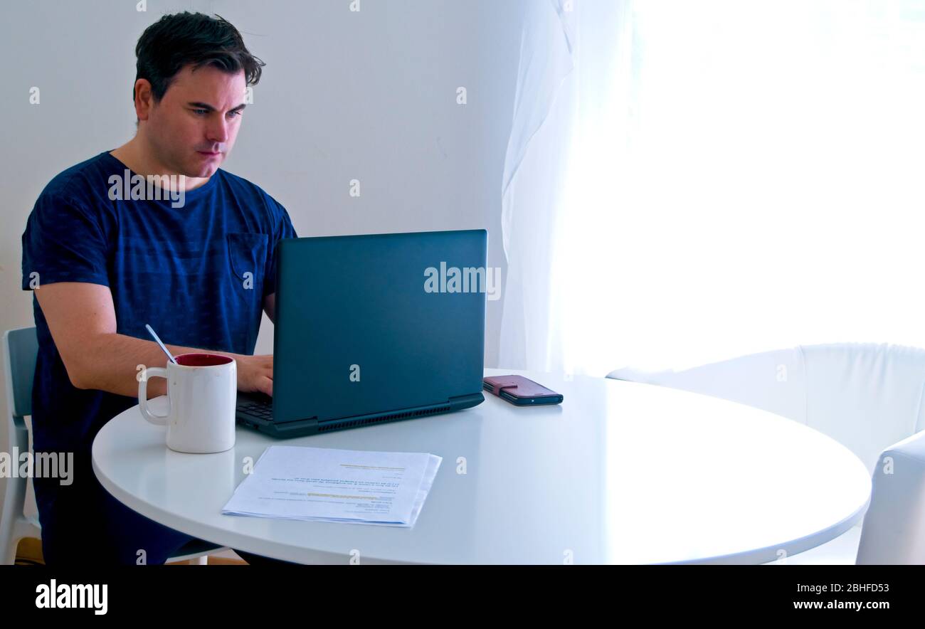 Jeune homme assis et travaillant sur un ordinateur portable à la maison. Concept de père de travail. Concept de télétravail . Banque D'Images