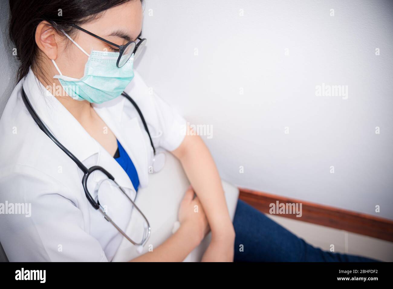 Jeune femme asiatique médecin porter masque à la sécurité Coronavirus assis sur le plancher dormir avec épuisement de travail, concept prendre soin de vous est de se hel Banque D'Images