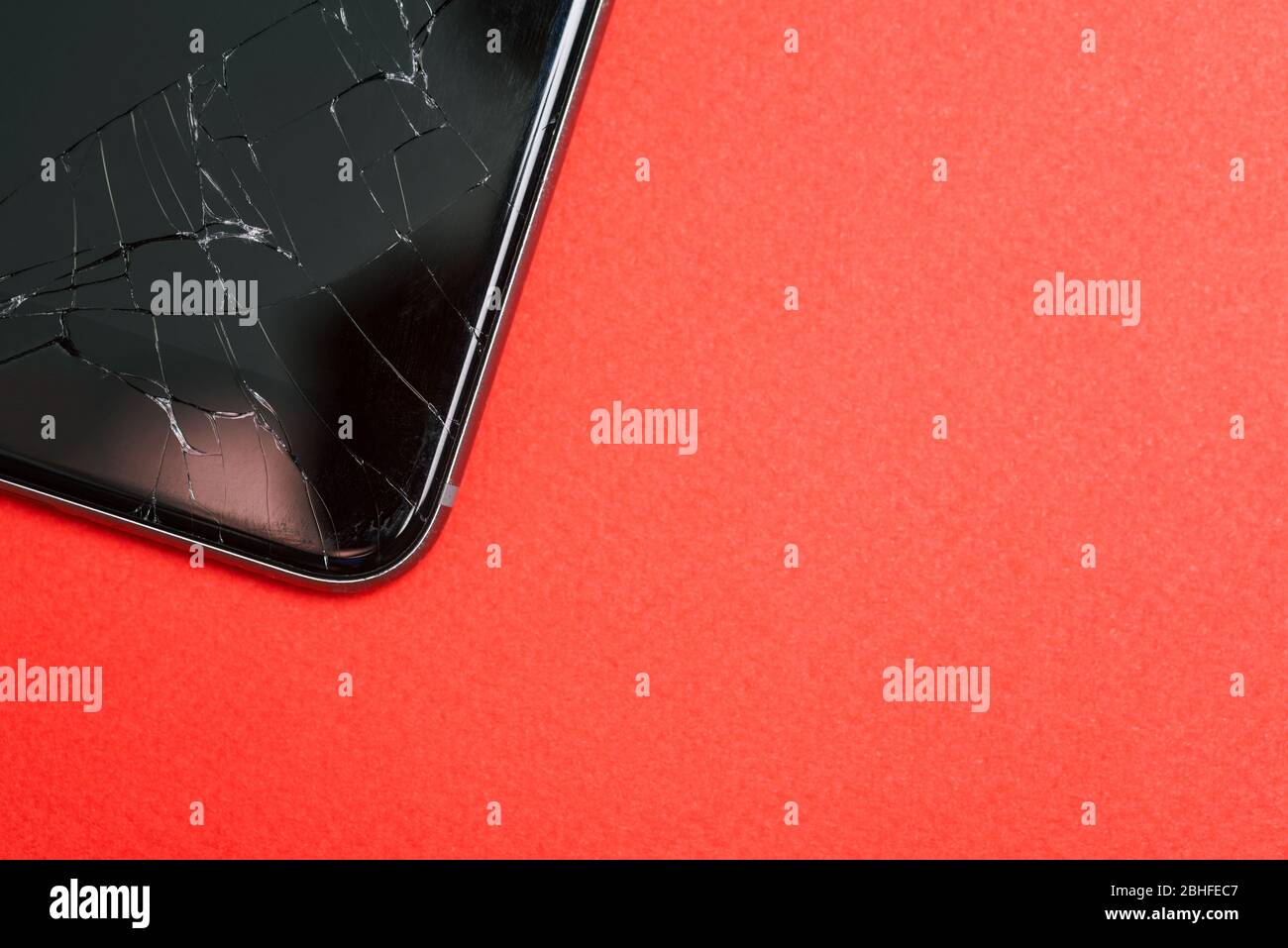 Téléphone portable avec fissures sur fond rouge. Un smartphone cassé. Gadget en verre cassé. Vue de dessus, espace de copie Banque D'Images