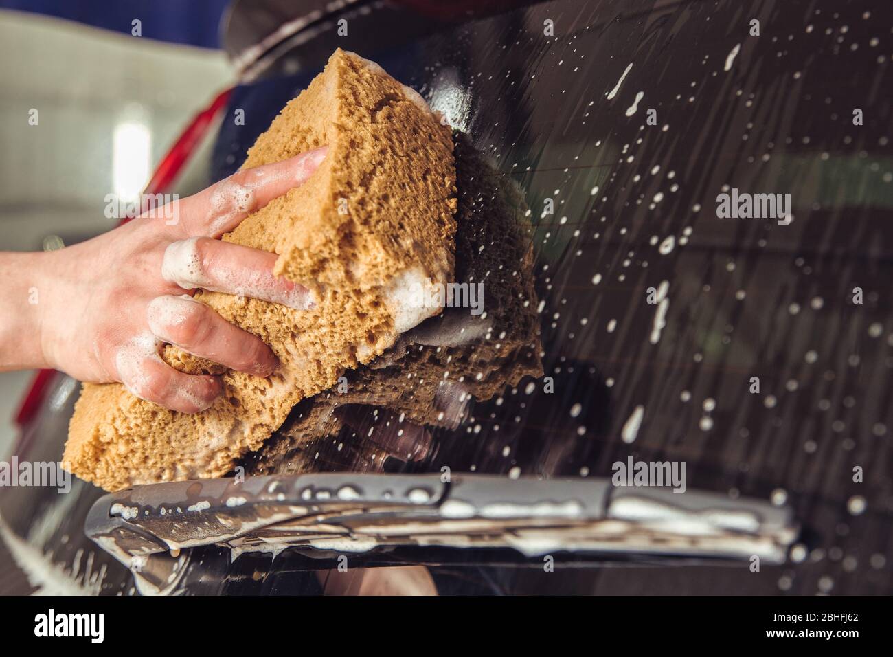 Porte de voiture en verre avec mousse et une main avec éponge en mousse Banque D'Images