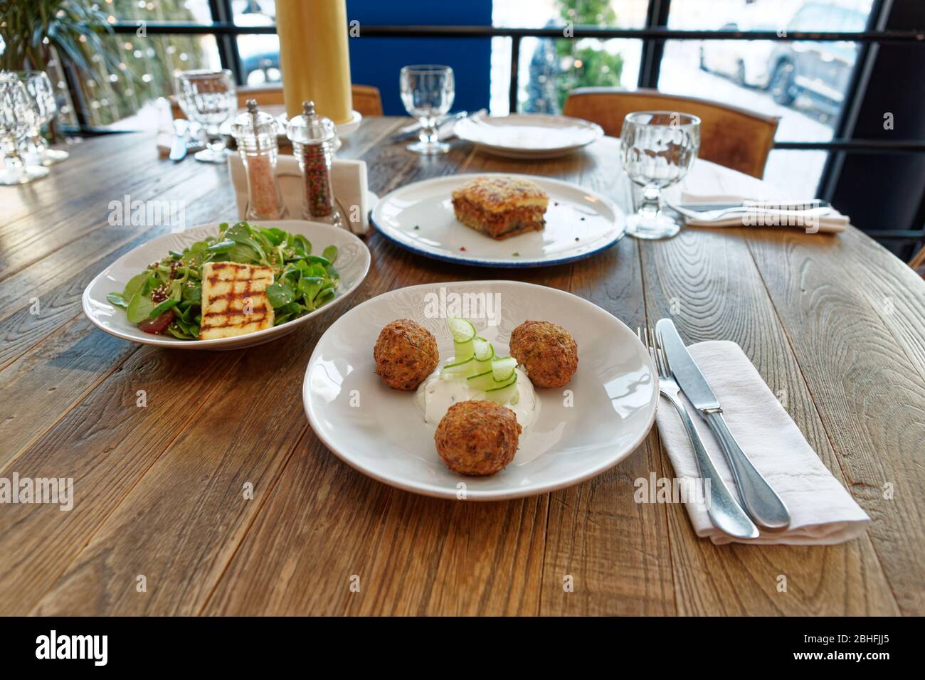 Le restaurant propose trois plats grecs : du fromage Saganaki frit, des moussaka et des beignets de courgettes Banque D'Images