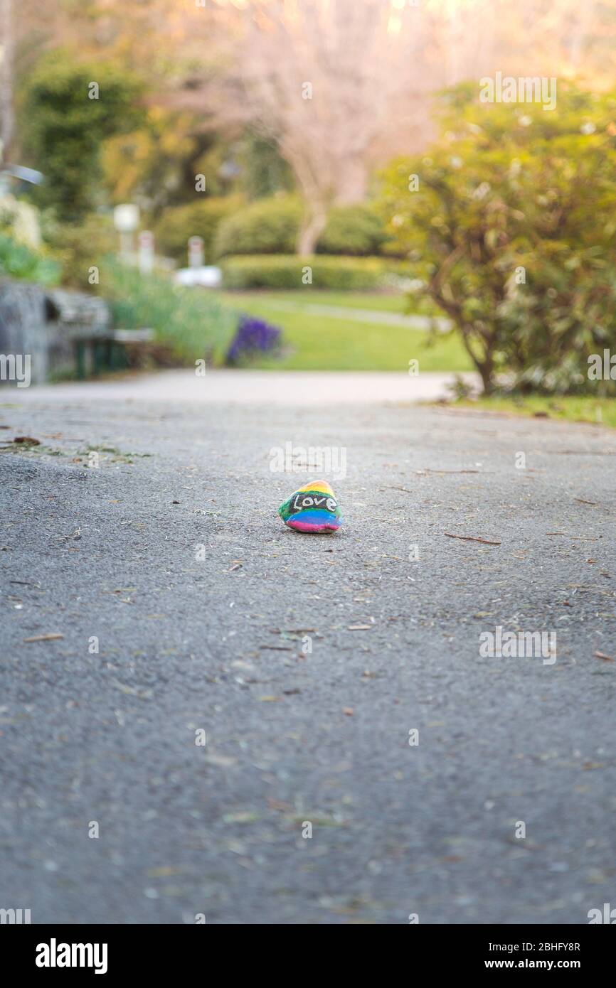Un rocher peint avec les couleurs de fierté lgbtq et le mot amour sur un sentier de randonnée dans un parc. Banque D'Images