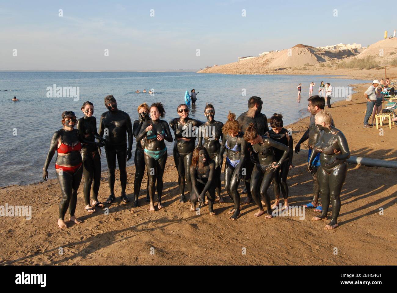 Mer morte, Jordanie - Janvier 2010: Groupe de touristes couverts de la boue noire de mer morte, près d'Aqaba. Banque D'Images