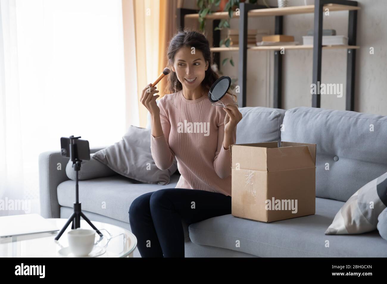 Belle jeune femme blogger influenceur appliquant des cosmétiques décoratifs sur le visage. Banque D'Images