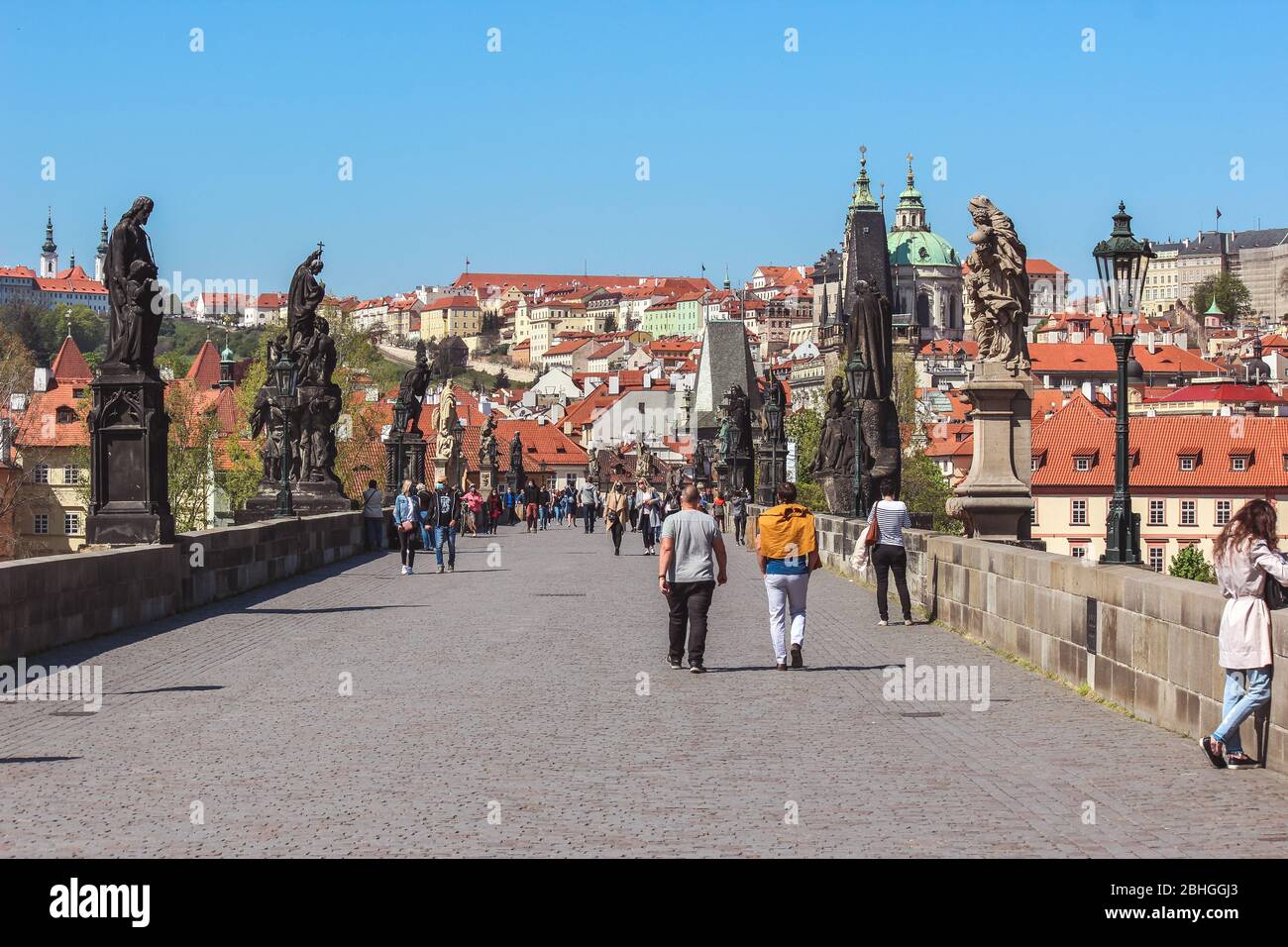 Prague, République tchèque - 23 avril 2020: Pont Charles avec des personnes portant des masques médicaux. Statues sur le pont. Vieille ville en arrière-plan. Centre-ville en cas de pandémie de coronavirus. COVID-19 crise. Banque D'Images