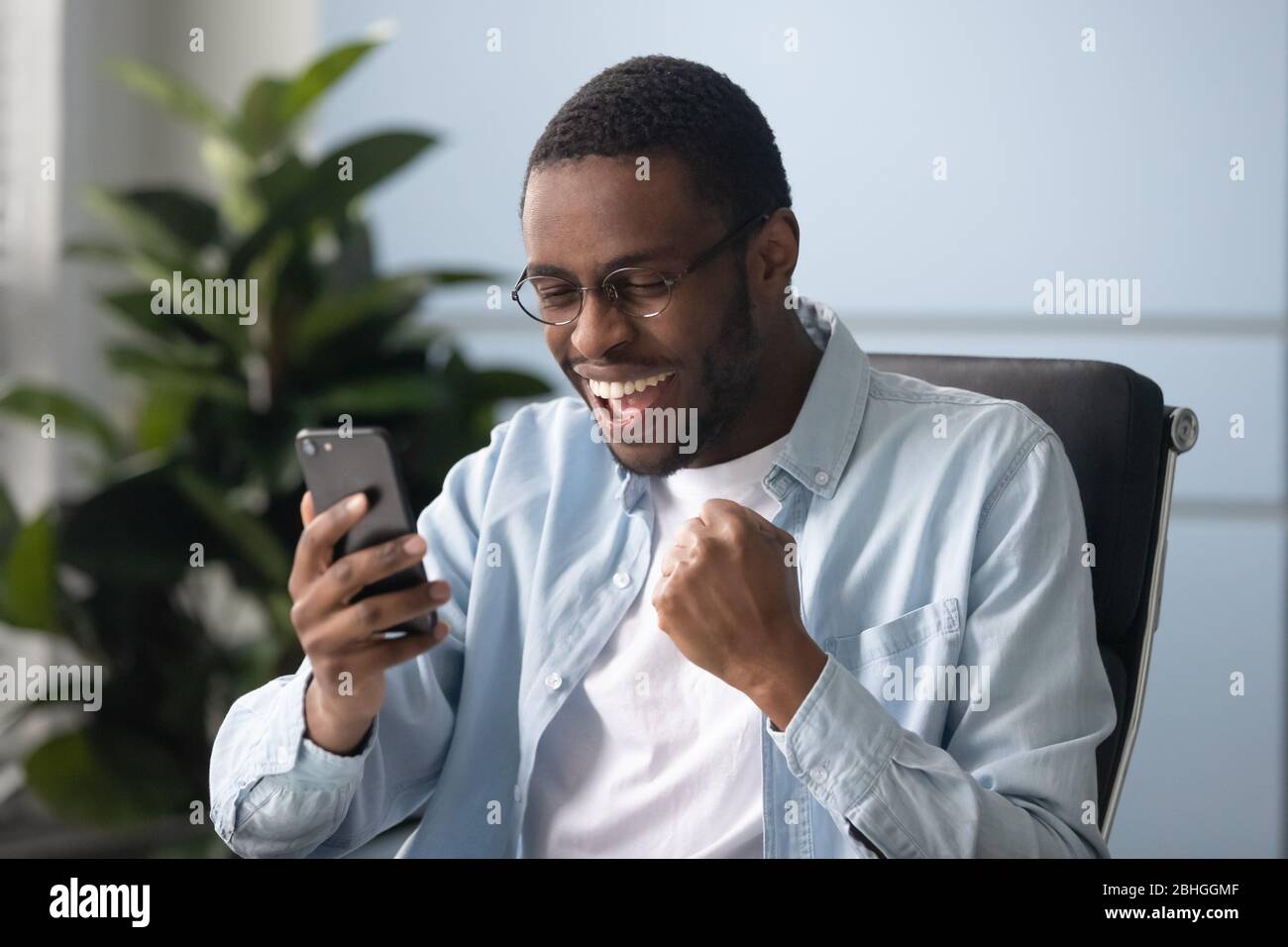 Un homme d'affaires afro-américain heureux avec des lunettes célébrant la réussite des affaires. Banque D'Images