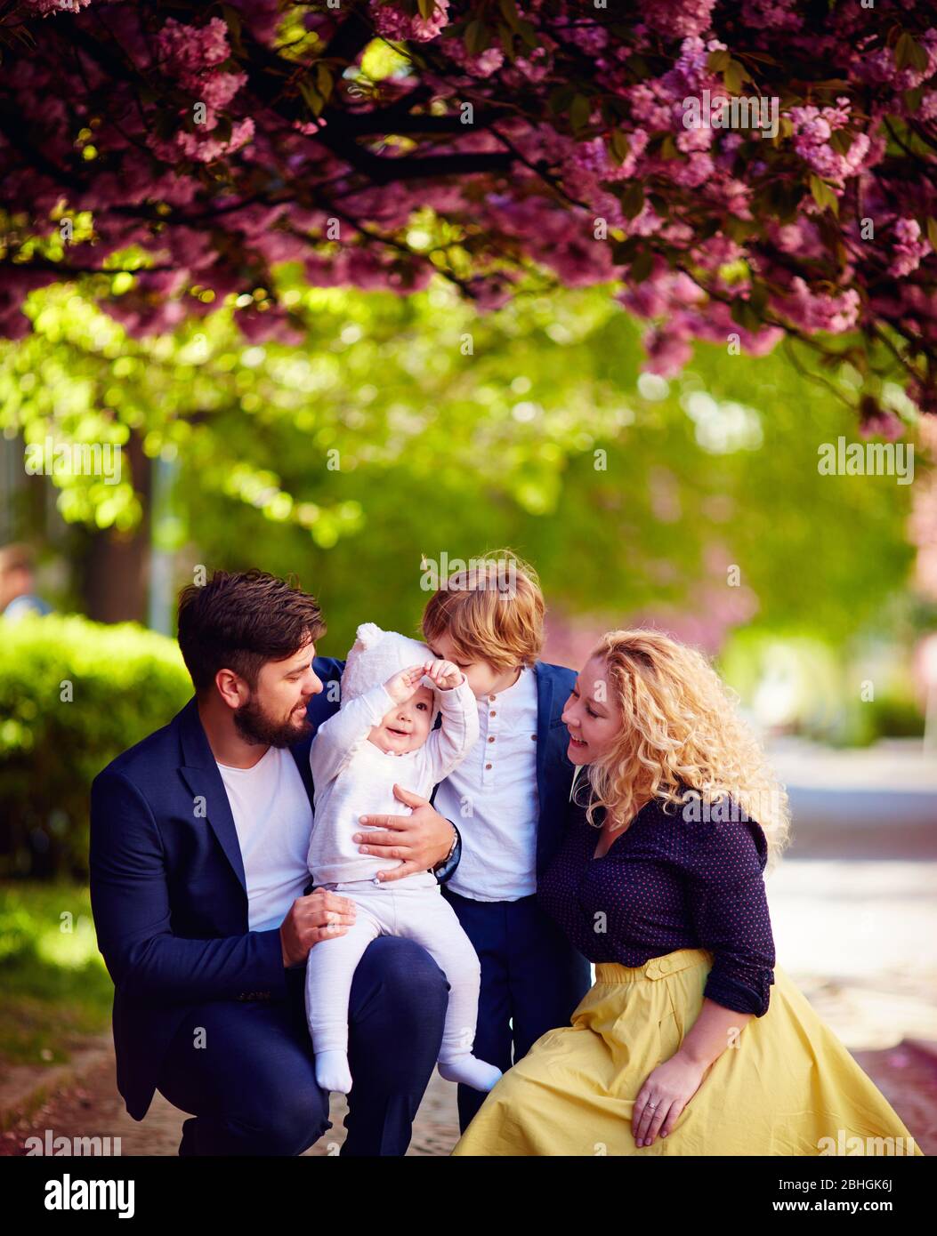 portrait de famille heureuse sur la promenade le long de la rue florissante de printemps Banque D'Images