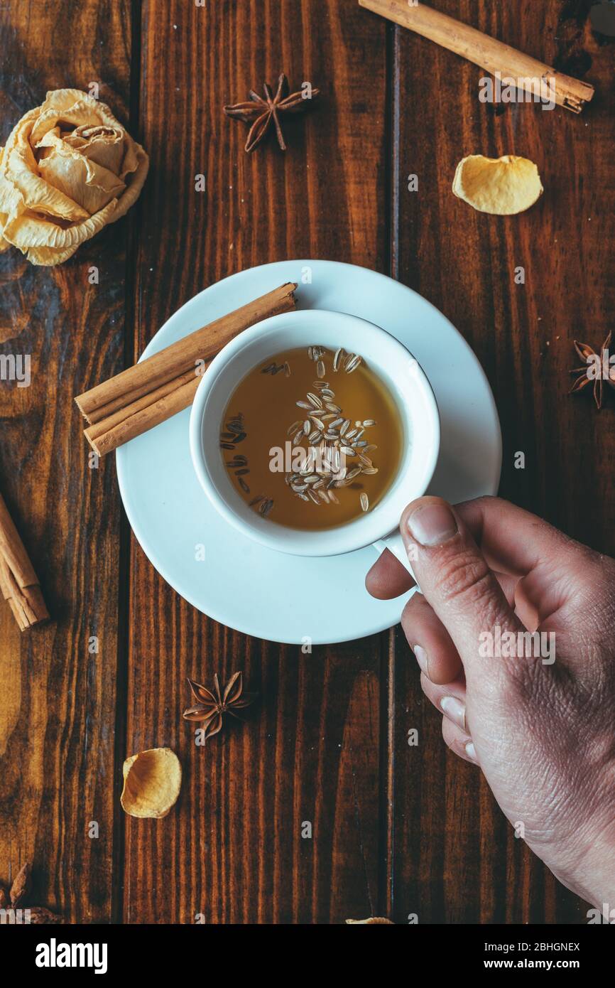 Tasse de thé blanc avec une main sur une table en bois et roses autour Banque D'Images