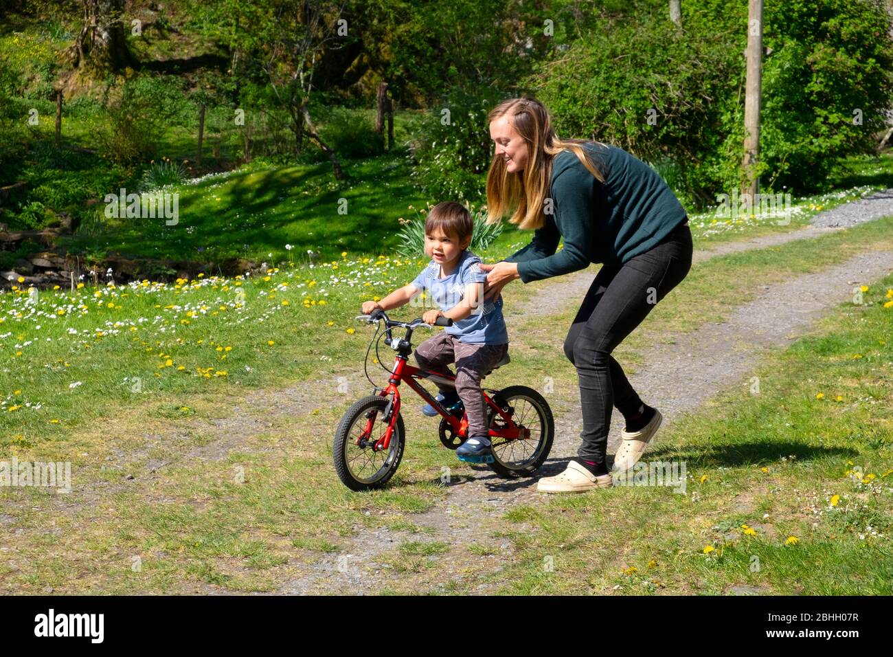 Mère jouant avec son jeune garçon de 3 ans l'aidant à apprendre à faire du vélo pendant le maintien dans Carmarthenshire Pays de Galles Royaume-Uni KATHY DEWITT Banque D'Images