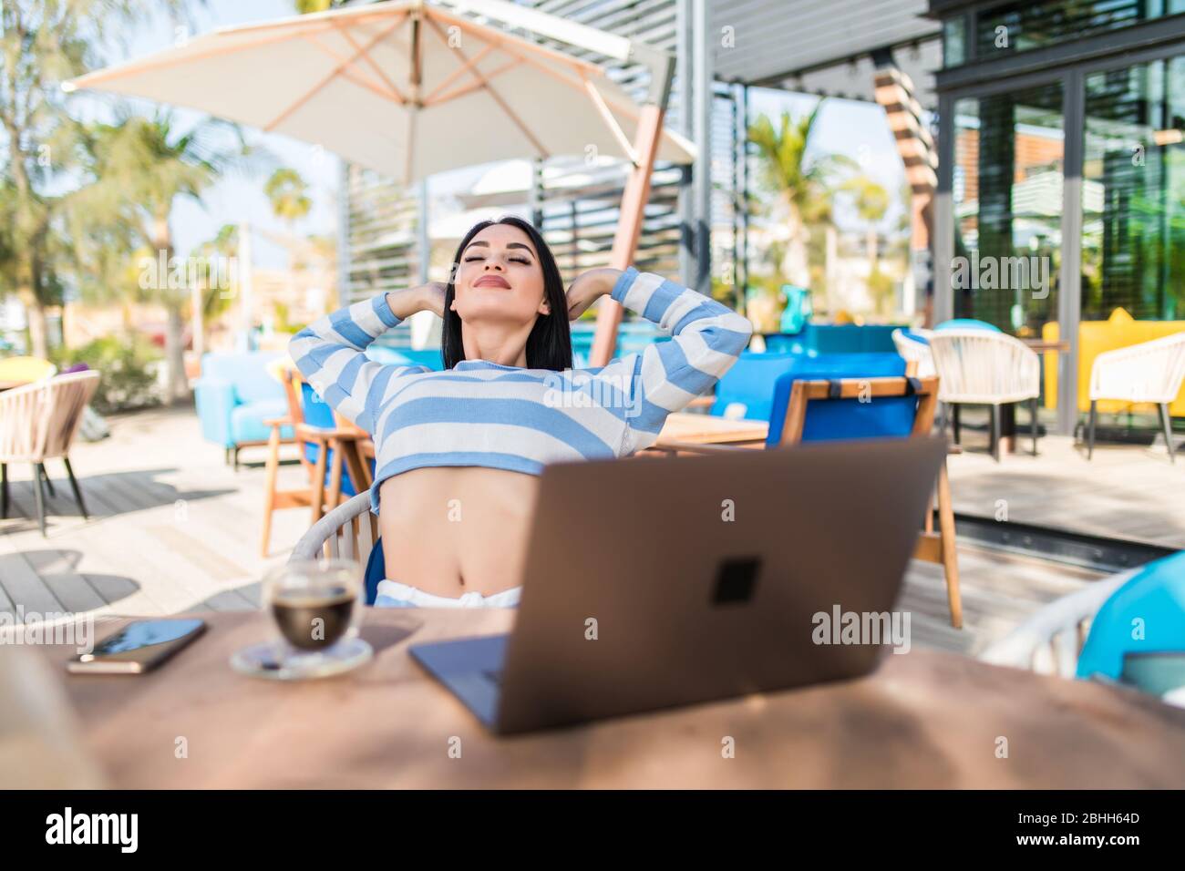 Jolie femme qui s'étire après avoir travaillé sur un ordinateur portable dans un café Banque D'Images