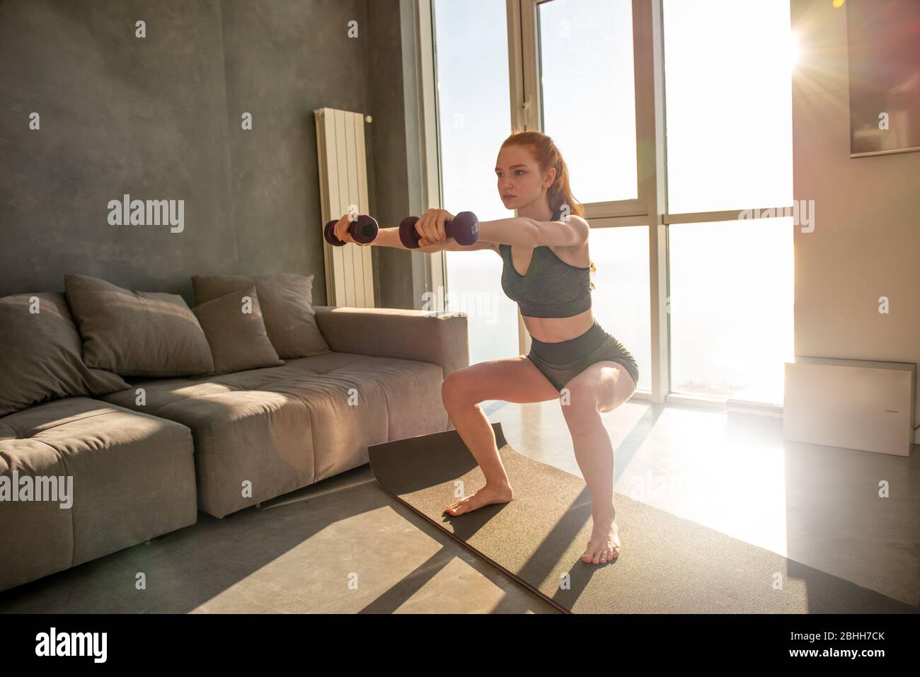 La jeune fille fait des exercices de gym pendant le lever du soleil. Elle est à la maison en raison de la quarantaine de coronavirus codiv-19 Banque D'Images