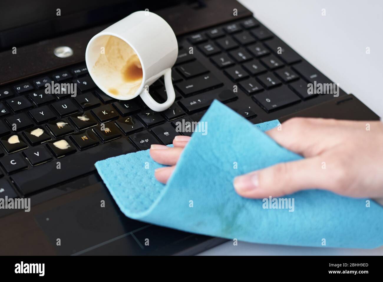 La main nettoie le café renversé sur le clavier de l'ordinateur portable avec un chiffon Banque D'Images La main nettoie le café renversé sur le clavier de l'ordinateur portable avec un chiffon Banque D'Images