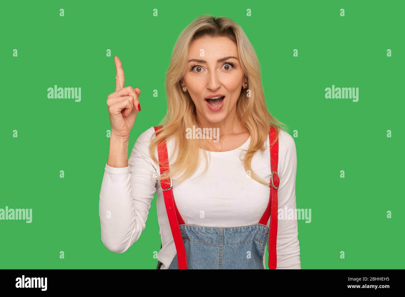 Eureka ! Portrait d'une femme adulte inspirée, interrogée dans des combinaisons en denim stylées pointant vers le haut, surpris par l'idée créative, la solution ingénieuse intelligente. ind Banque D'Images