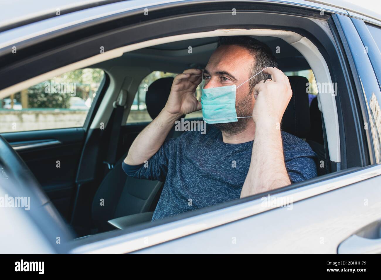 L'homme portant un masque de protection pour éviter l'infection du virus et les désouses polluées à l'intérieur de sa voiture. Soins de santé, coronavirus, grippe Banque D'Images