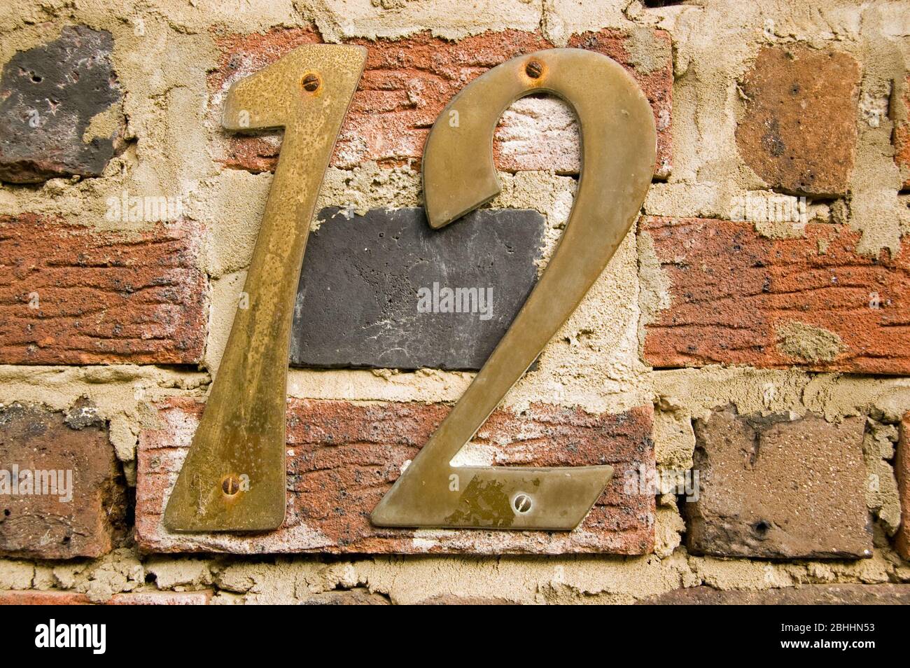 Numéro 12 sur un vieux mur de brique à l'extérieur d'une maison. Banque D'Images