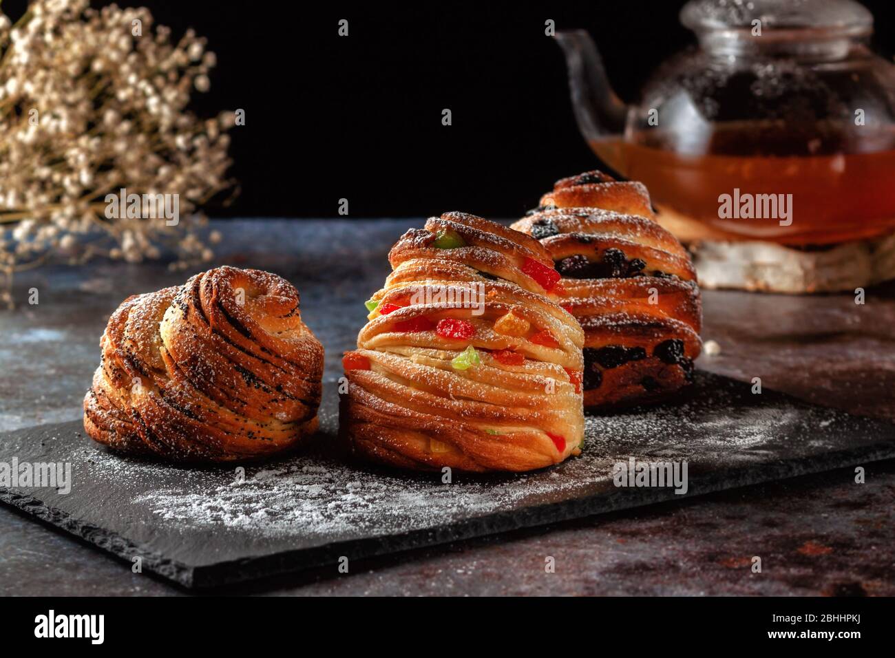 Kraffins aux raisins secs, fruits confits et graines de pavot, arrosés de sucre en poudre. Banque D'Images
