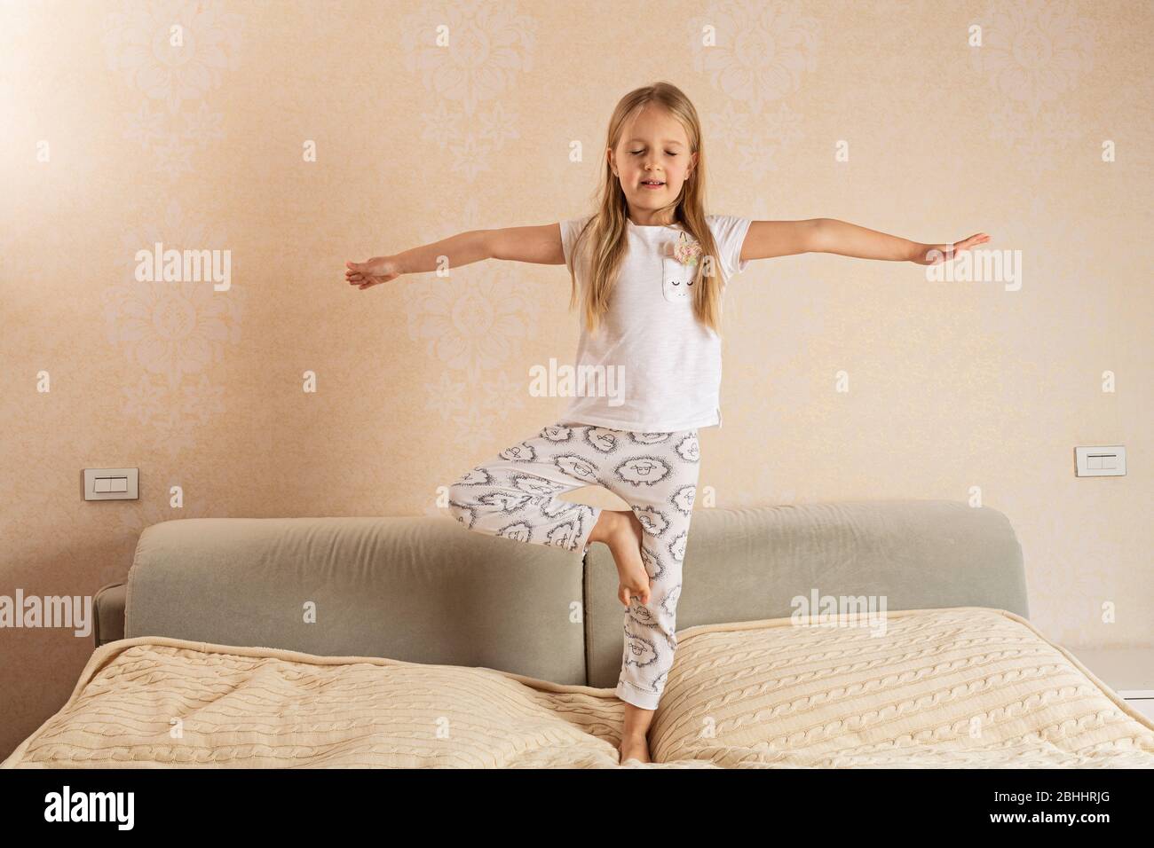 Belle petite fille en pyjama s'amuse bien sur le lit à la maison. Restez chez vous pendant le verrouillage du coronavirus covid-19 Banque D'Images