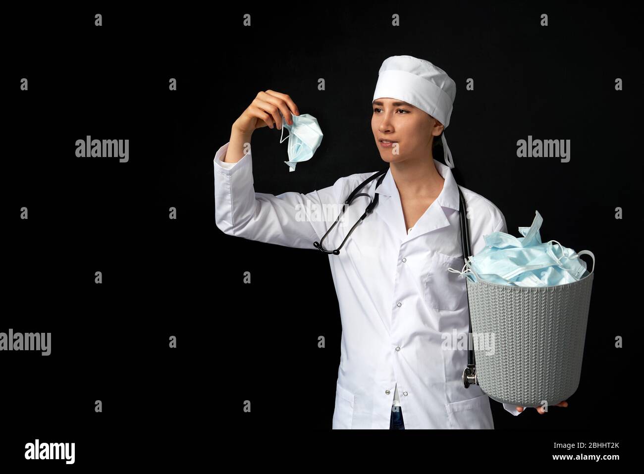 Le médecin tient un seau rempli de masques faciaux usagés, les jetant comme symbole de fin d'épidémie Banque D'Images