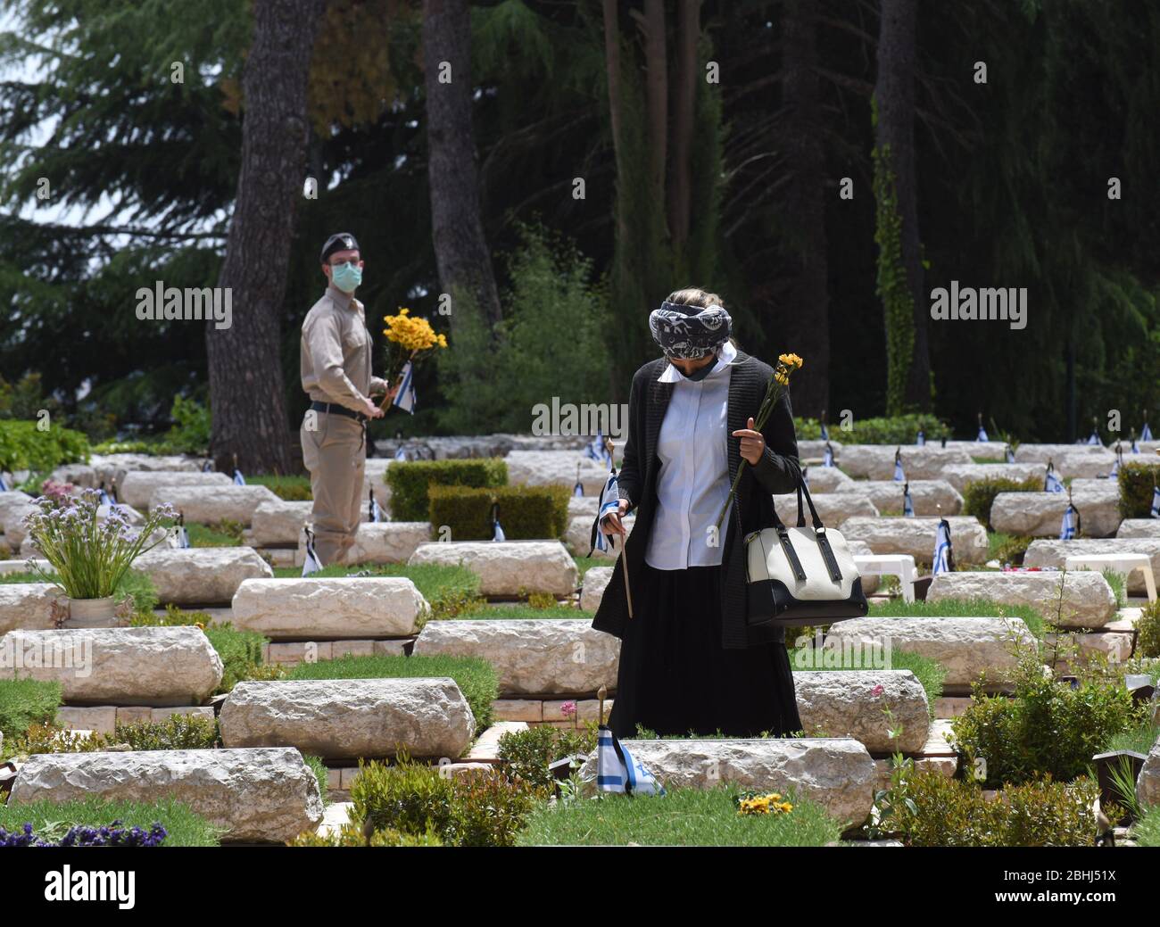 Jérusalem, Israël. 26 avril 2020. Un israélien possède un drapeau national et des fleurs à la tombe d'un soldat tombé, avant le jour commémoratif, dans le Mt. Cimetière militaire Herzl, le dimanche 26 avril, à Jérusalem. Les familles endeuillées ne pourront pas visiter le cimetière le jour commémoratif d'Israël pour les soldats tombés et les victimes de terreur, qui commence au coucher du soleil, le 27 avril, dans un effort pour arrêter la propagation de la COVID-19. Photo de Debbie Hill/UPI crédit: UPI/Alay Live News Banque D'Images