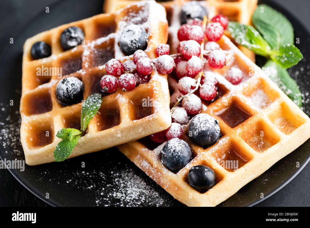 Gaufres belges carrées avec baies et sucre glace sur une plaque noire. Gaufres sucrées savoureuses Banque D'Images