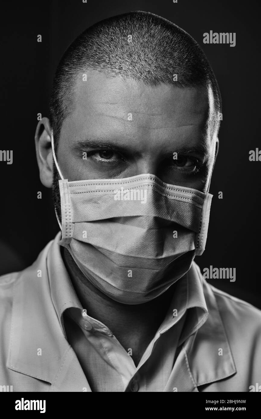 Gros plan portrait caucasien confiance visage de médecin mâle dans le masque de protection bleu regardant l'appareil photo. Professionnel de la santé Banque D'Images