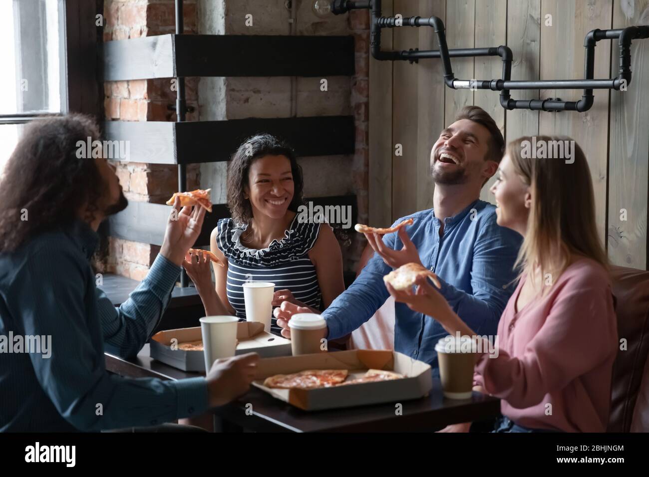 Joyeux amis divers ont plaisir à manger ensemble Banque D'Images
