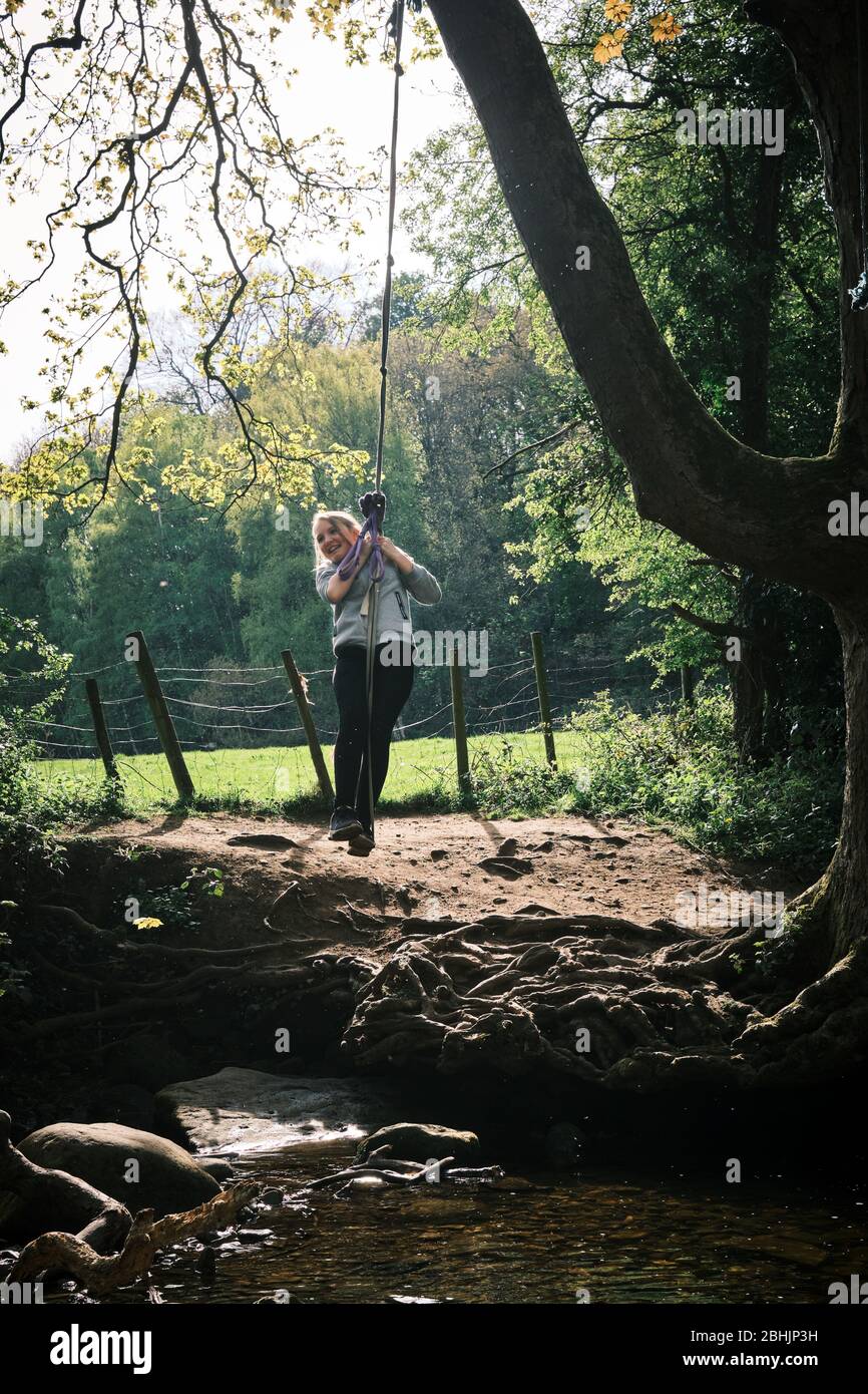 Une fille rit alors qu'elle balance sur une corde dans les bois à Shipley Glen, Saltaire, West Yorkshire. ROYAUME-UNI Banque D'Images