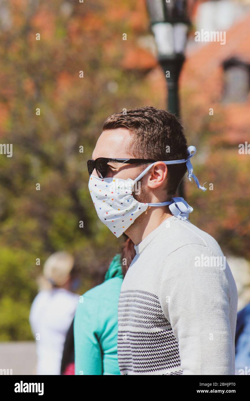 Jeune homme avec lunettes de soleil et masque en tissu cousu photographié sur le pont Charles à Prague, en République tchèque. Brouillé dans l'arrière-plan. Voyager, tourisme pendant coronavirus. COVID-19. Banque D'Images