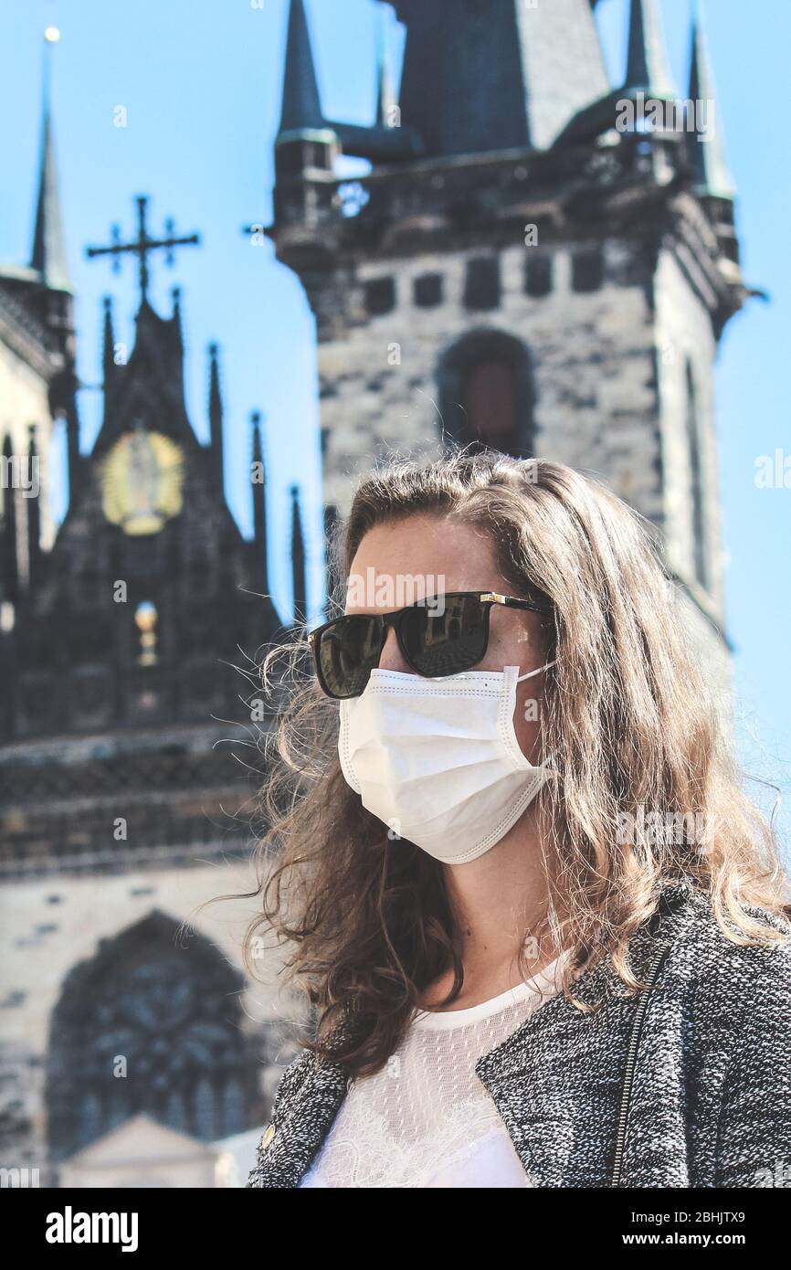 Jeune femme avec lunettes de soleil et masque médical photographié devant l'église notre-Dame avant Tyn à Prague, en République tchèque. Voyager, tourisme pendant coronavirus. Concept COVID-19. Banque D'Images